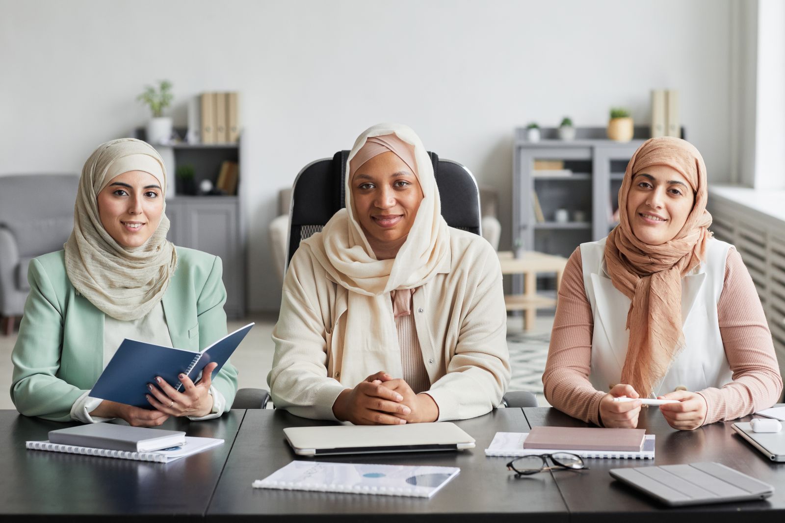 Three Muslim businesswomen in hijabs in a modern office